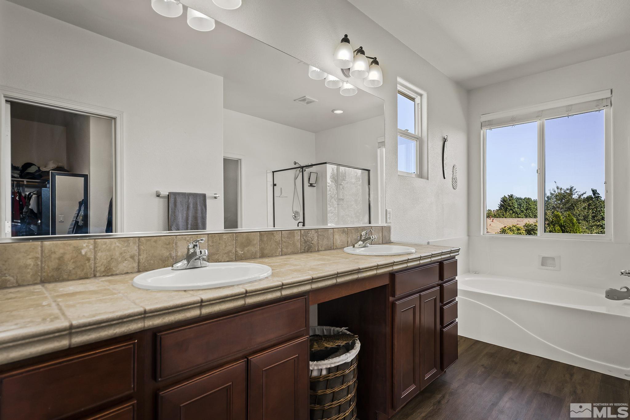 375 Sondrio Way Reno, NV 89521 - Photo 22 of 36 a bathroom with a granite countertop sink a large mirror and a bathtub