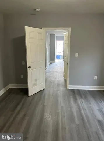 a view of an empty room with wooden floor and closet