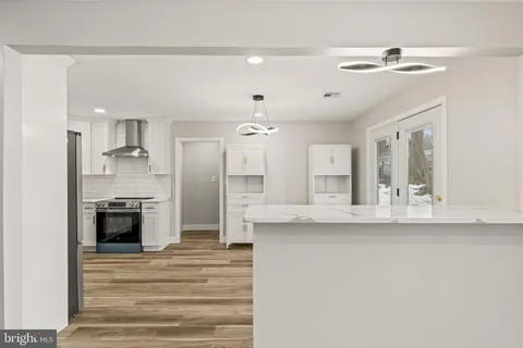 a large white kitchen with a refrigerator a stove a sink dishwasher and a fireplace with wooden floor