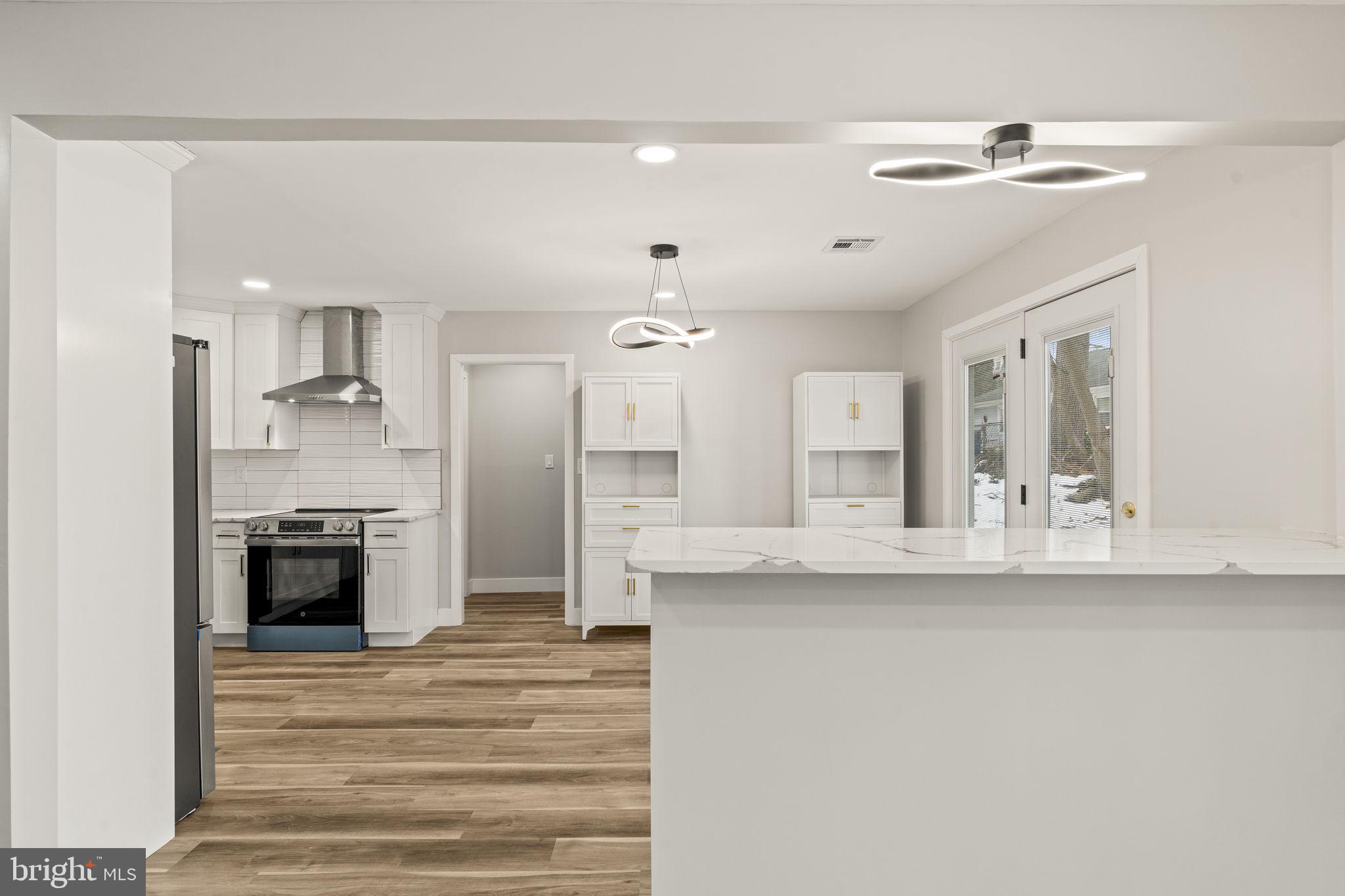 24 Pilgrim Lane Willingboro, NJ 08046 - Photo 13 of 40 a large white kitchen with a refrigerator a stove a sink dishwasher and a fireplace with wooden floor