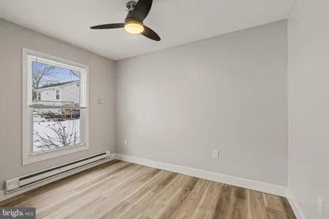 a view of an empty room with window and wooden floor