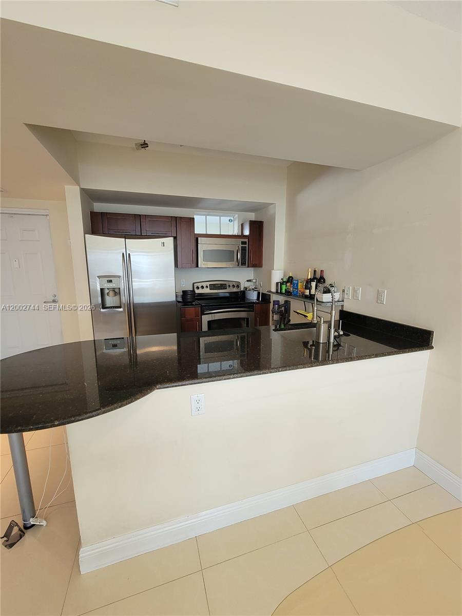 7290 Southwest 90th Street, Unit 403 Miami, FL 33156 - Photo 5 of 18 a kitchen with granite countertop a refrigerator and a stove top oven