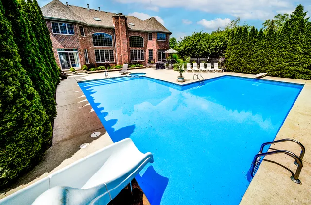 a view of swimming pool with outdoor seating and house in the background