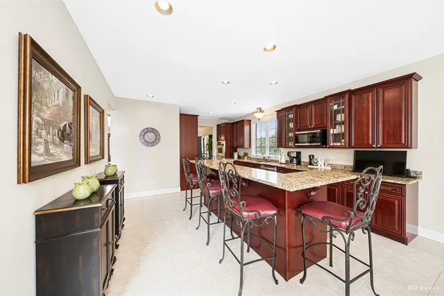 a kitchen with stainless steel appliances kitchen island granite countertop a refrigerator a stove a sink a dining table and chairs with wooden floor