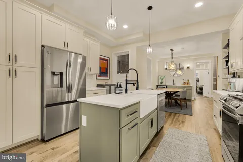 a kitchen with stainless steel appliances granite countertop a refrigerator a stove a sink a dining table and chairs with wooden floor