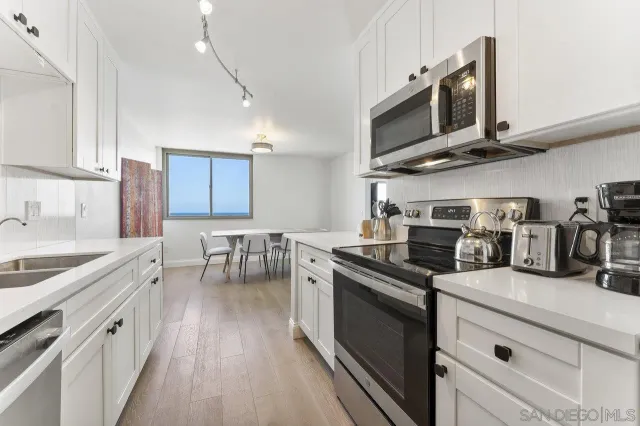 a kitchen with stainless steel appliances granite countertop a sink a stove oven a counter space and cabinets