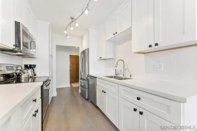 a kitchen with white cabinets sink and stove