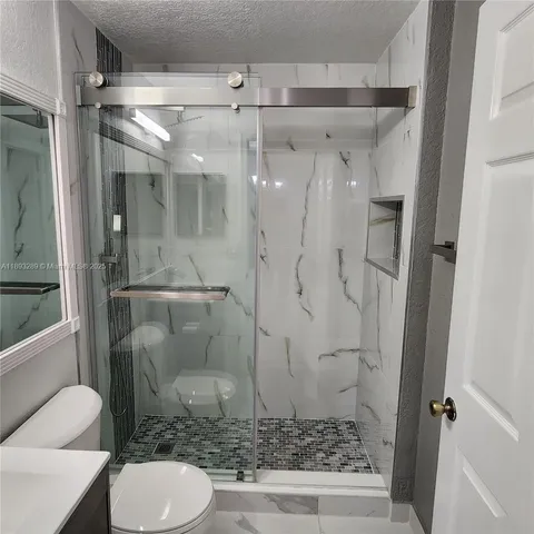 a bathroom with a granite countertop shower a toilet and a sink