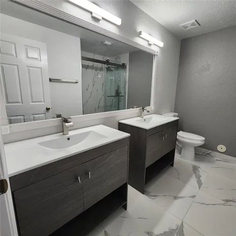 a bathroom with a double vanity sink mirror and toilet