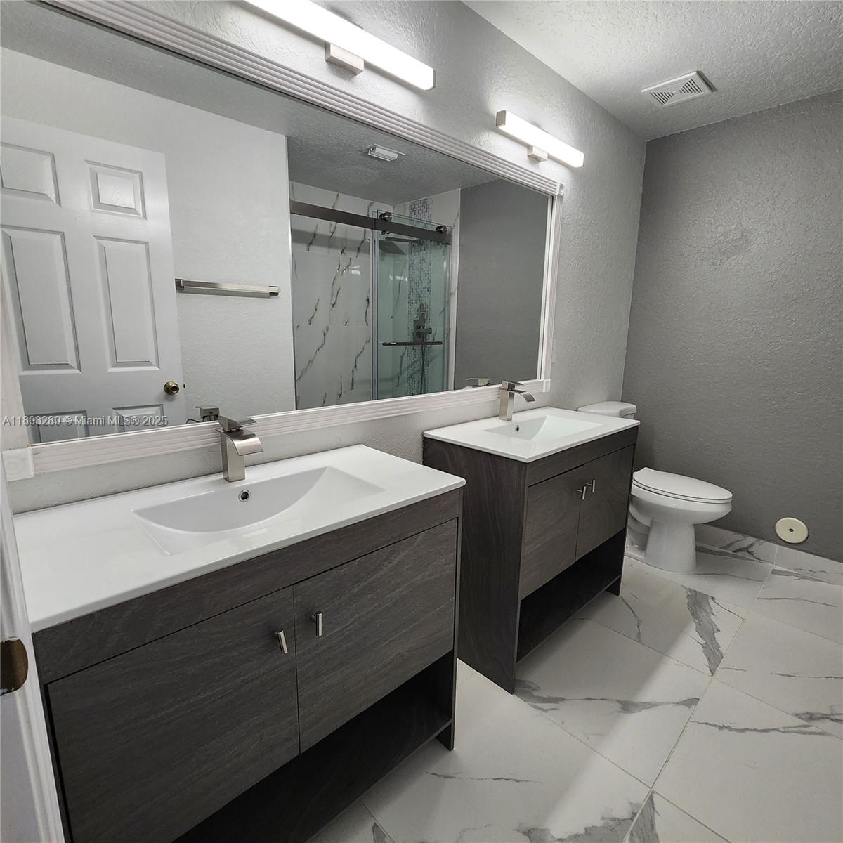 2941 Riverside Drive, Unit 102 Coral Springs, FL 33065 - Photo 28 of 37 a bathroom with a double vanity sink mirror and toilet
