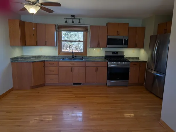 a kitchen with stainless steel appliances granite countertop a stove a sink dishwasher a refrigerator and a stove with wooden floor