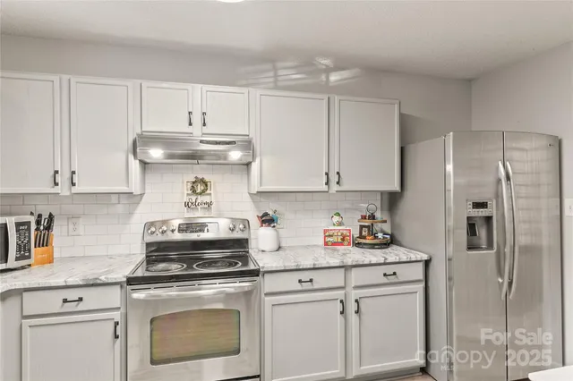 a kitchen with white cabinets and appliances