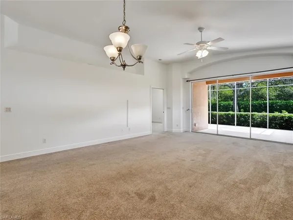 a view of an empty room with a chandelier fan and a large window
