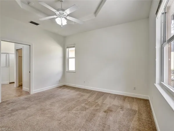 an empty room with windows and ceiling fan