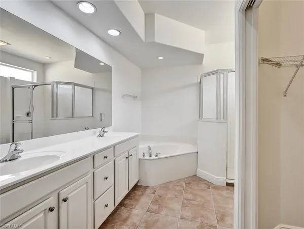 a spacious bathroom with a double vanity sink a mirror and a bathtub