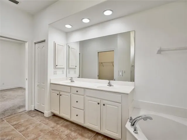 a spacious bathroom with a double vanity sink a mirror and a bathtub