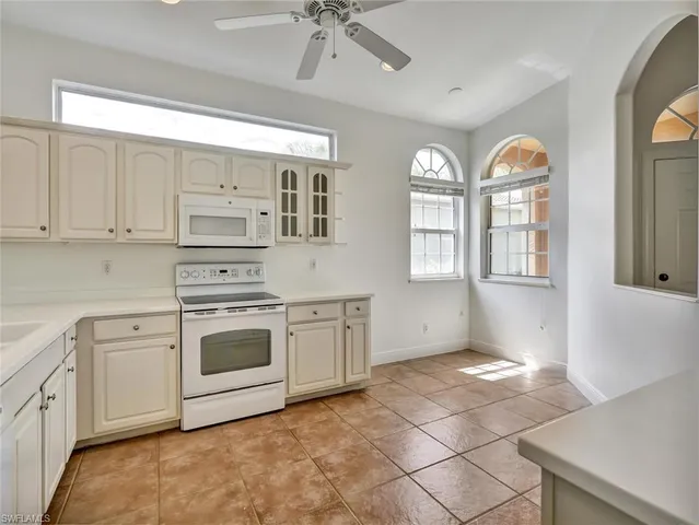 a kitchen with stainless steel appliances granite countertop a stove a sink dishwasher and white cabinets with wooden floor