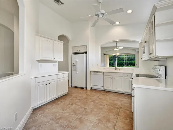 a large white kitchen with a sink stove and cabinets
