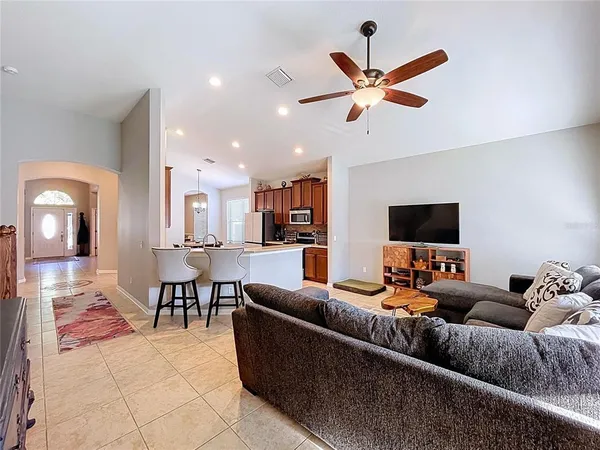 a living room with furniture kitchen view and a window