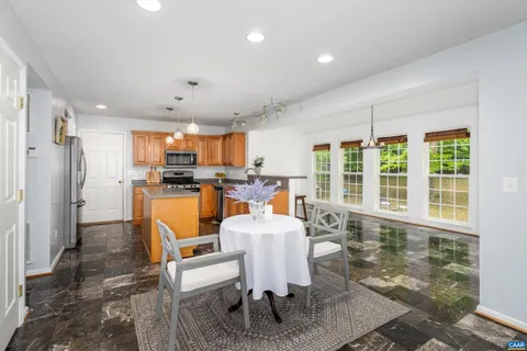 a dining room with stainless steel appliances granite countertop a table chairs and a refrigerator