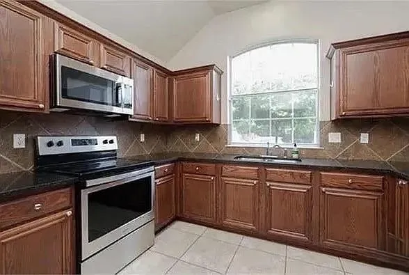 a kitchen with stainless steel appliances granite countertop white cabinets granite counter tops and a window