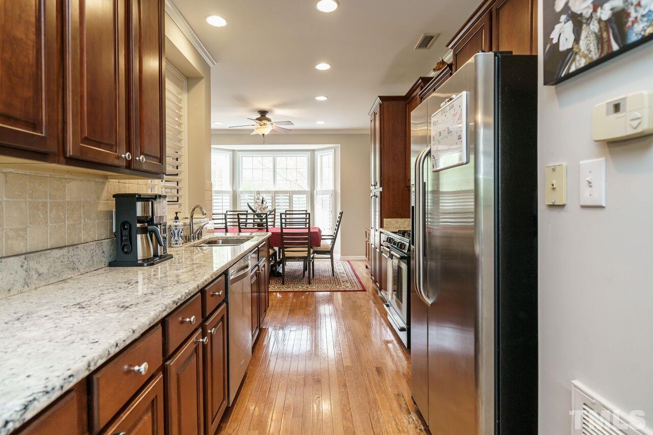 6903 Middleboro Drive Raleigh, NC 27612 - Photo 12 of 26 a kitchen with kitchen island granite countertop a large window and stainless steel appliances