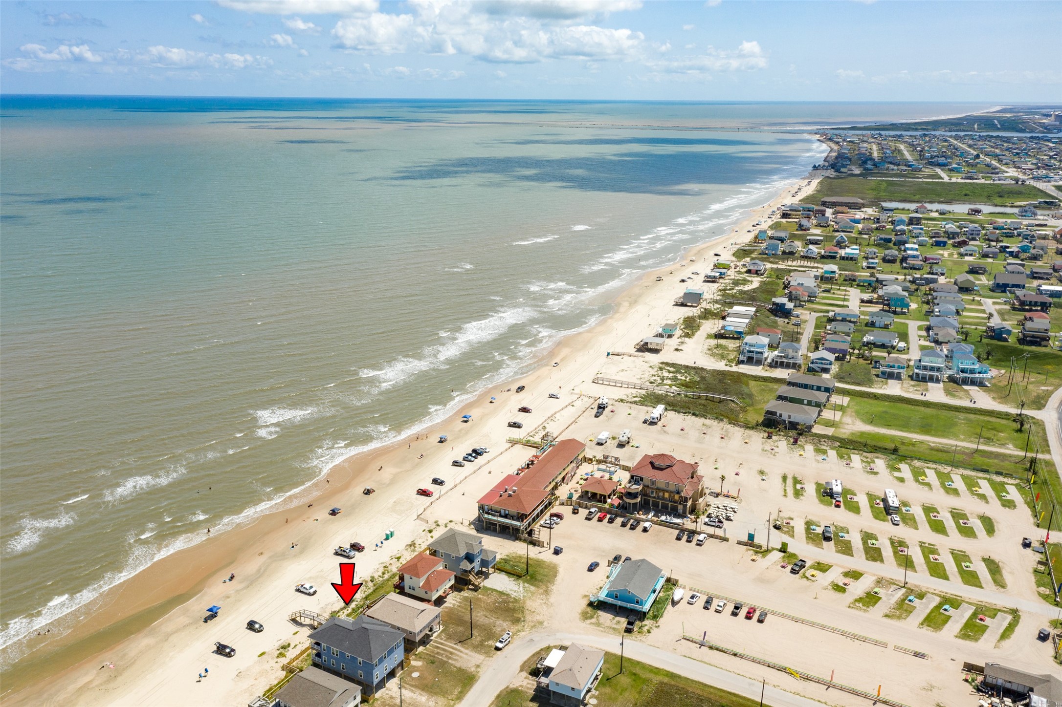 109 A Santar Loop, Unit A Surfside Beach, TX 77541 - Photo 11 of 43 This aerial photo showcases a beachfront property with direct beach access, surrounded by a picturesque coastal community. The house is prominently marked with a red arrow, highlighting its prime location near the shoreline. Perfect for those seeking a seaside lifestyle.