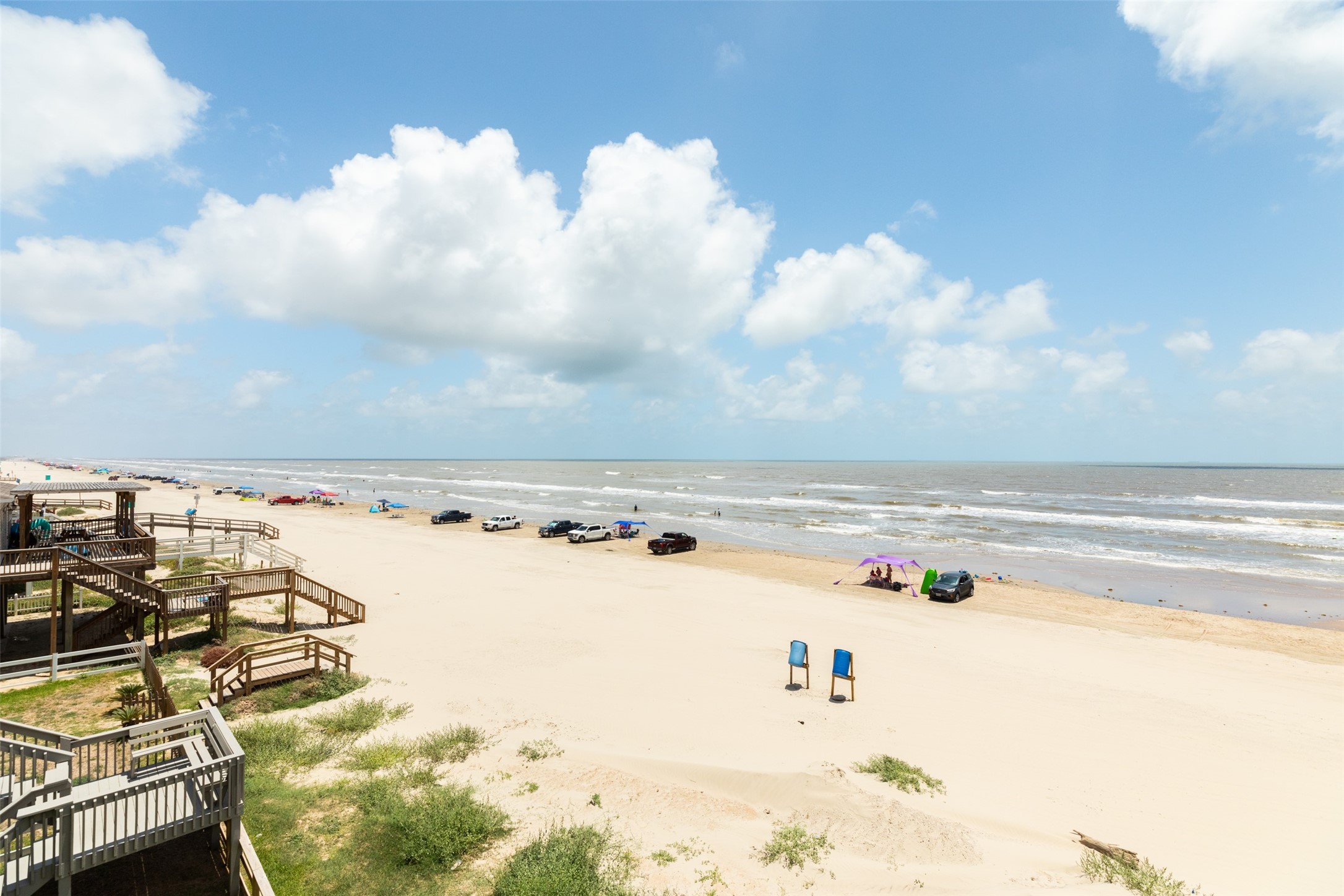 109 A Santar Loop, Unit A Surfside Beach, TX 77541 - Photo 21 of 43 This photo showcases a beautiful beachfront with sandy shores and gentle waves. The area includes wooden walkways and ample space for beach activities, perfect for enjoying coastal living.