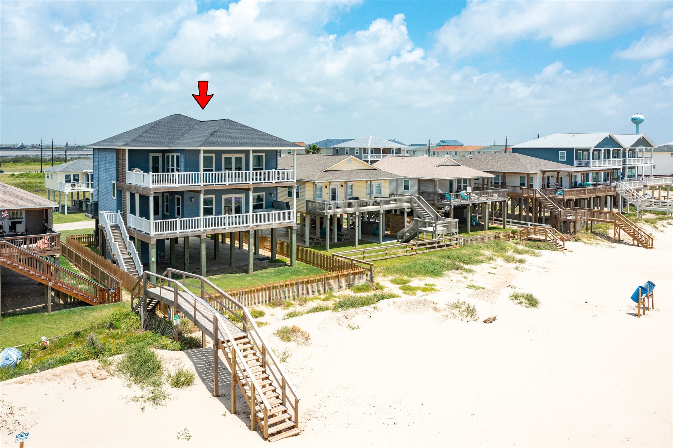 109 A Santar Loop, Unit A Surfside Beach, TX 77541 - Photo 5 of 43 Elevated beachfront home with spacious decks, offering stunning ocean views. Located in a row of similar stilt houses, it features direct beach access via a wooden walkway. Ideal for seaside living or vacation retreats.
