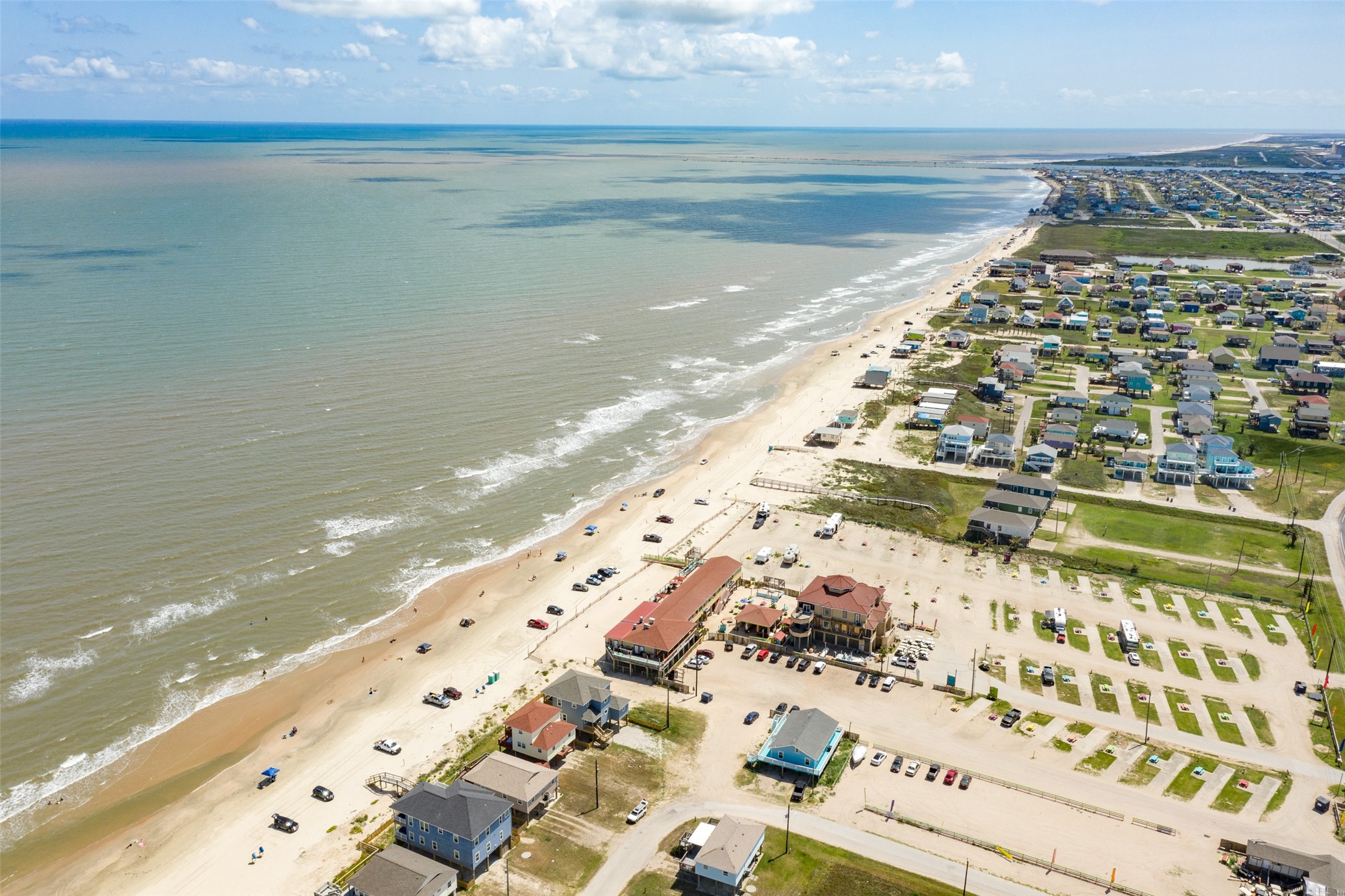 109 A Santar Loop, Unit A Surfside Beach, TX 77541 - Photo 10 of 43 This aerial photo showcases a scenic coastal community with beachfront homes and a broad shoreline. The area features a mix of residential properties, ample parking, and easy beach access, ideal for those seeking a relaxed seaside lifestyle.