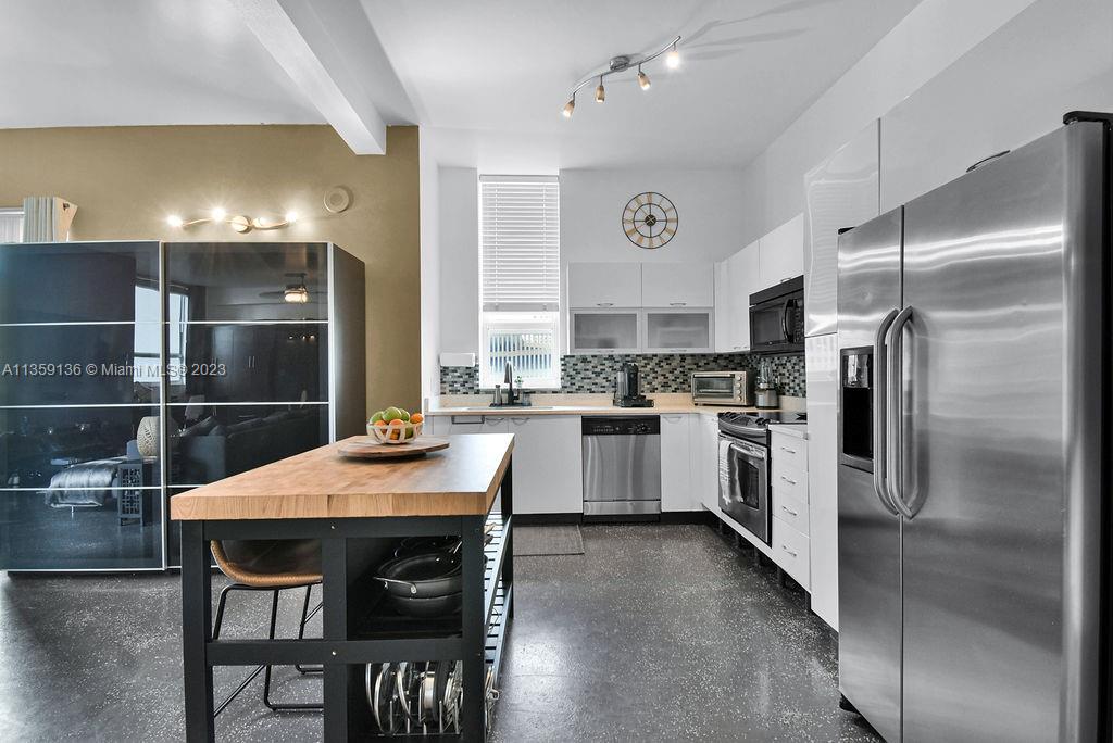 234 Northeast 3rd Street, Unit 507 Miami, FL 33132 - Photo 19 of 48 a kitchen with stainless steel appliances a table chairs refrigerator and cabinets