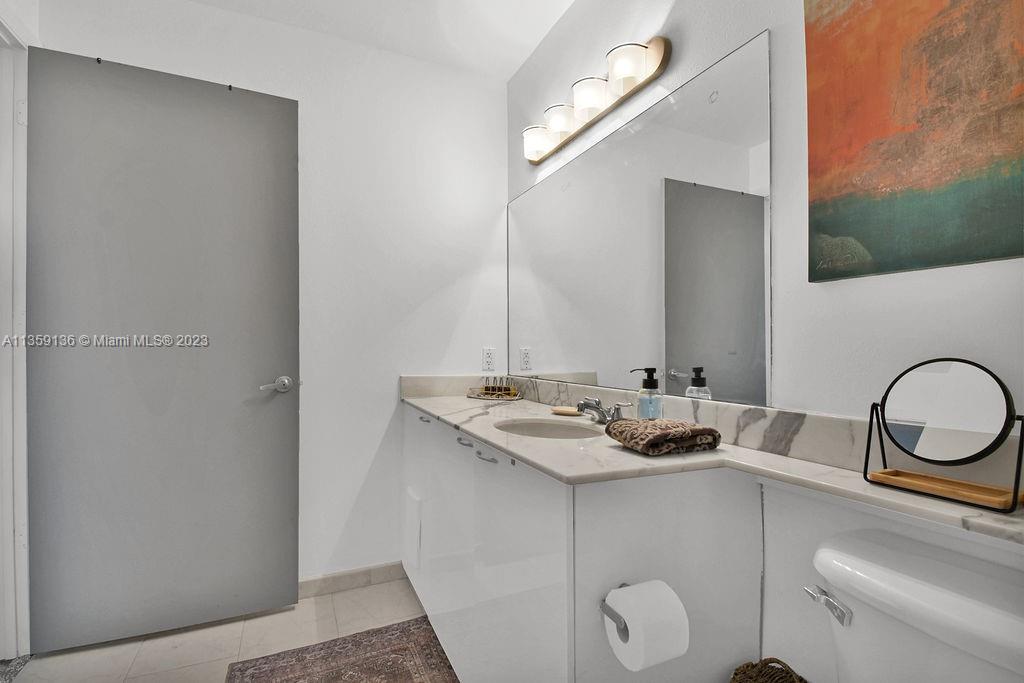 234 Northeast 3rd Street, Unit 507 Miami, FL 33132 - Photo 27 of 48 a bathroom with a granite countertop sink and a mirror
