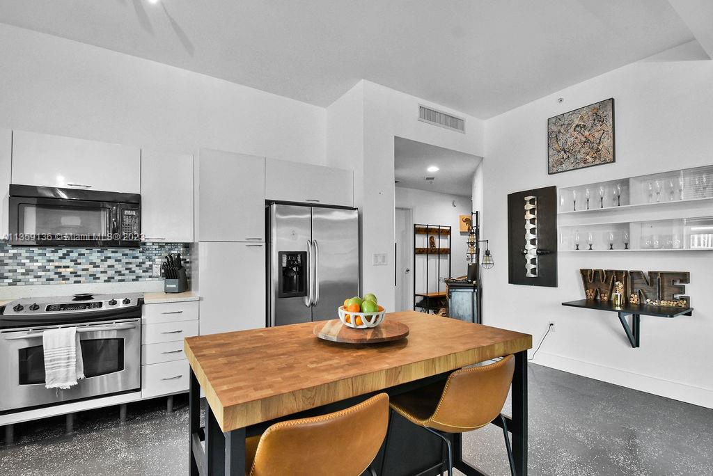 234 Northeast 3rd Street, Unit 507 Miami, FL 33132 - Photo 31 of 48 a kitchen with stainless steel appliances a dining table and chairs