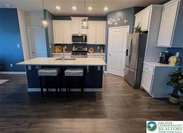 a kitchen with stainless steel appliances a dining table chairs refrigerator and microwave