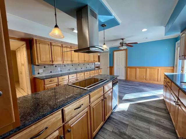 a kitchen with stainless steel appliances granite countertop a sink a stove and a wooden floors
