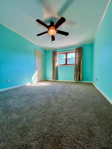 en empty room with windows and ceiling fan
