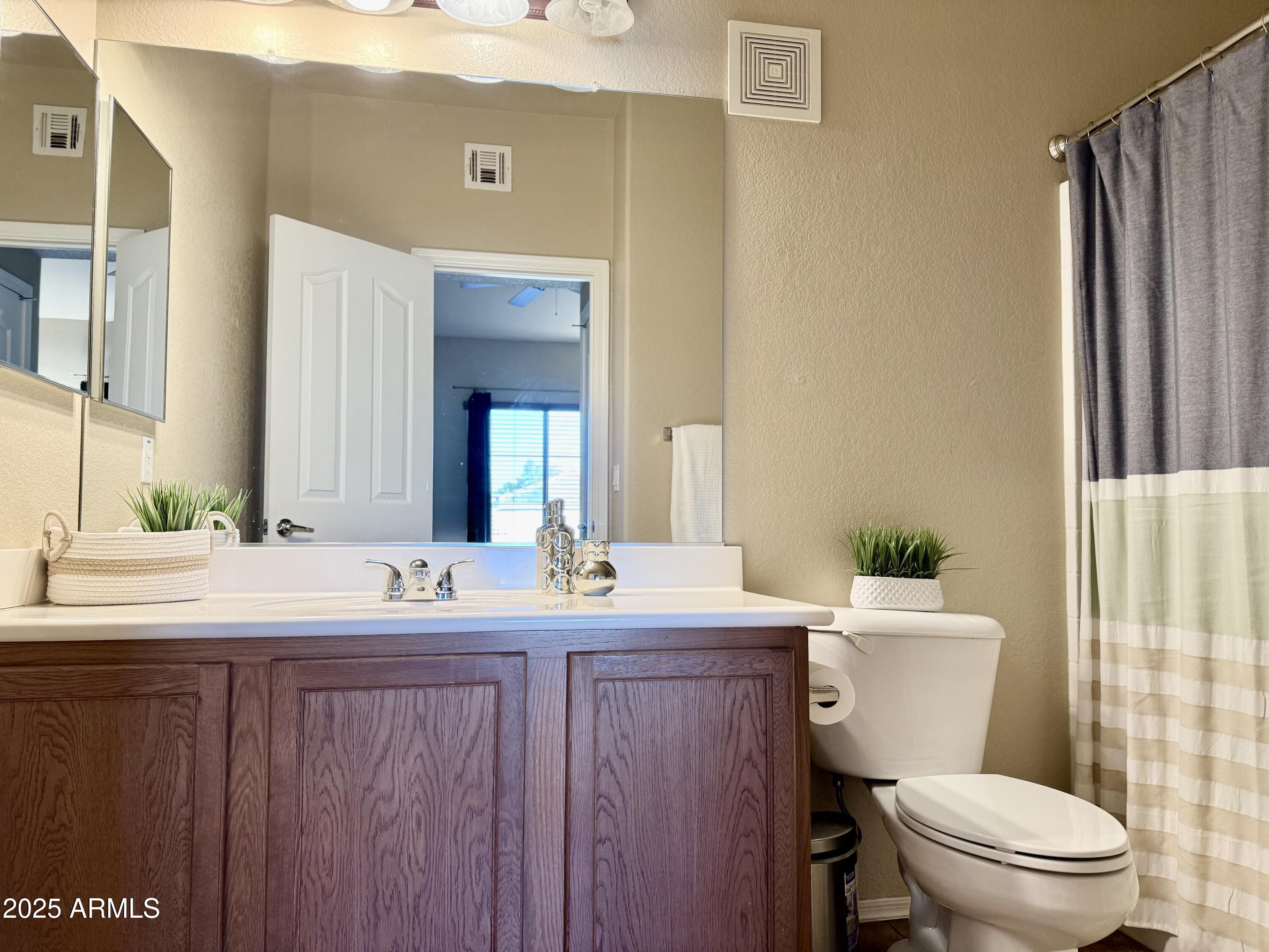2150 West Alameda Road, Unit 1032 Phoenix, AZ 85085 - Photo 14 of 39 a bathroom with a granite countertop toilet sink and mirror
