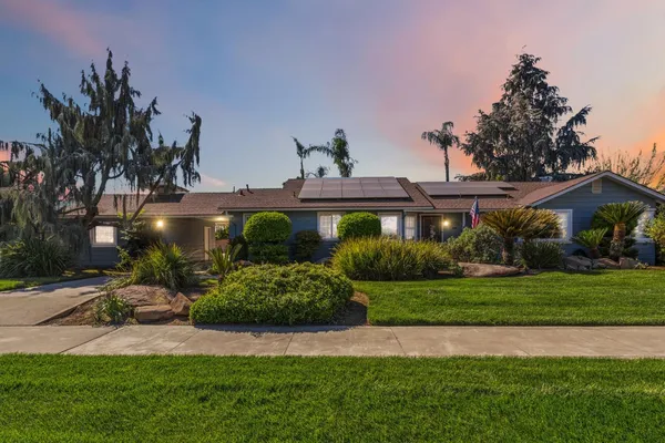 a front view of a house with a yard and potted plants