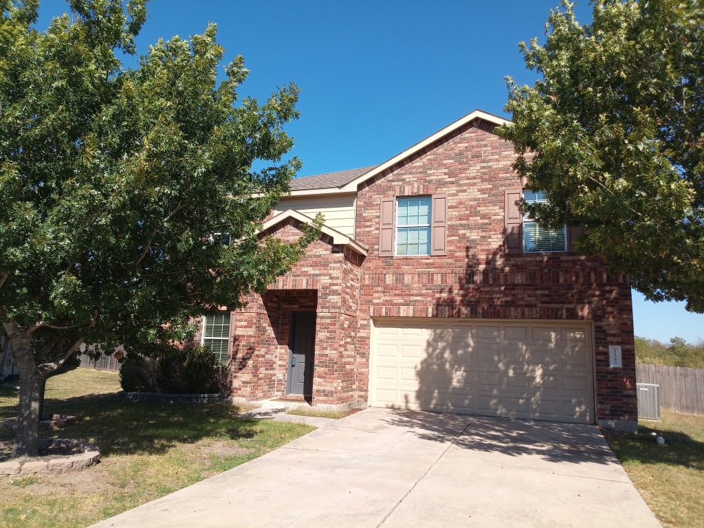 View of front of house featuring driveway, brick siding, and a garage