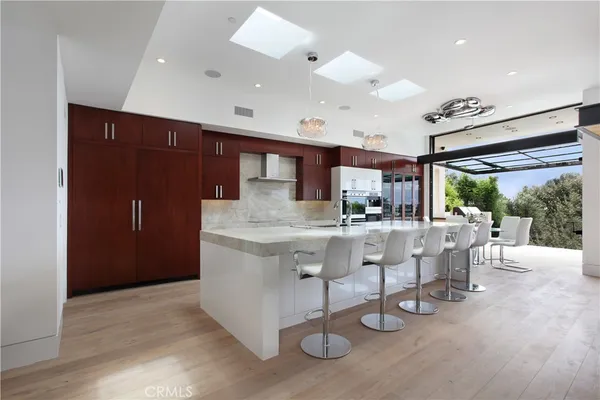a kitchen with stainless steel appliances kitchen island granite countertop a table chairs and a grill