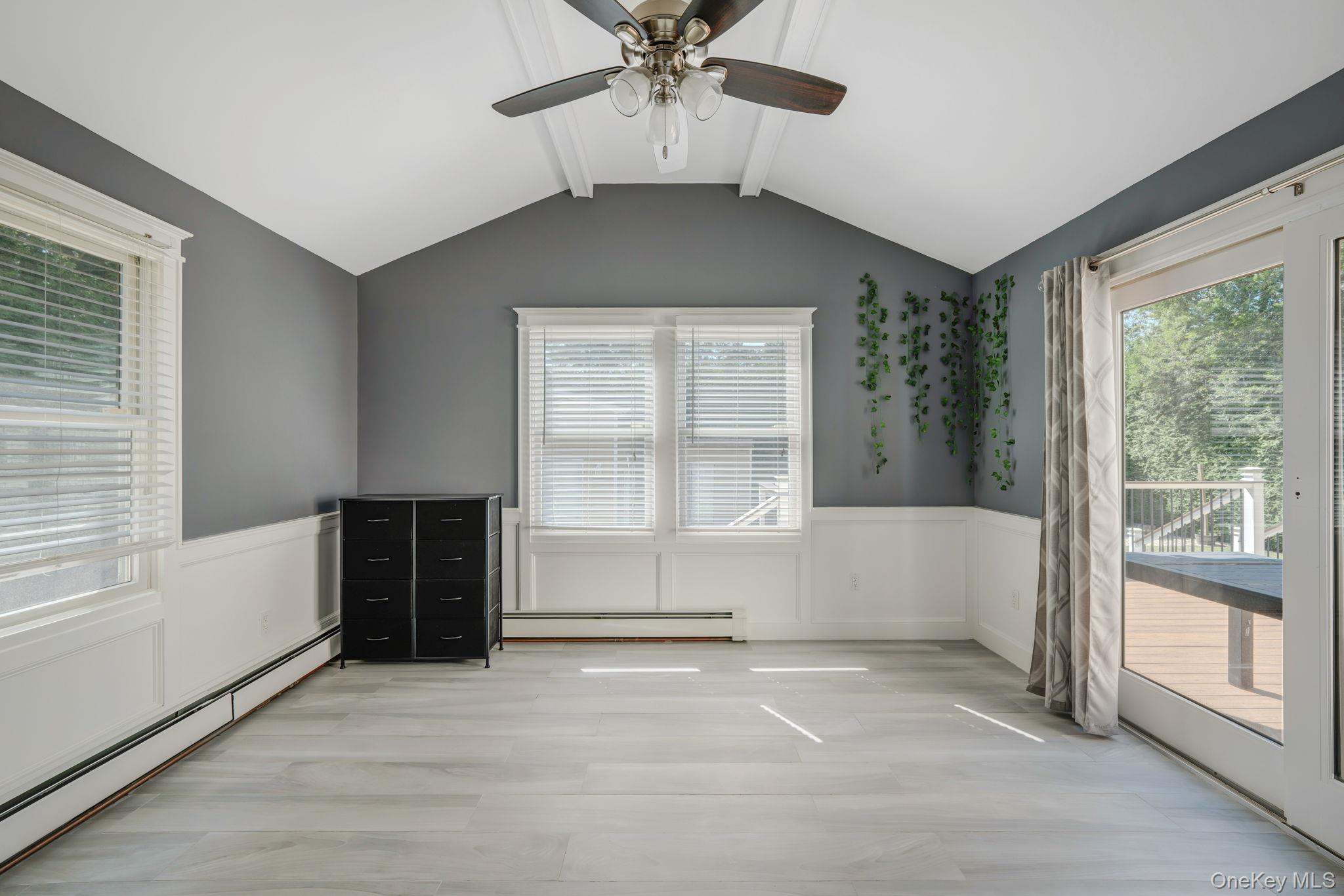 183 Old Country Road Speonk, NY 11972 - Photo 24 of 48 Unfurnished bedroom featuring a baseboard heating unit, access to outside, wainscoting, a decorative wall, and a ceiling fan