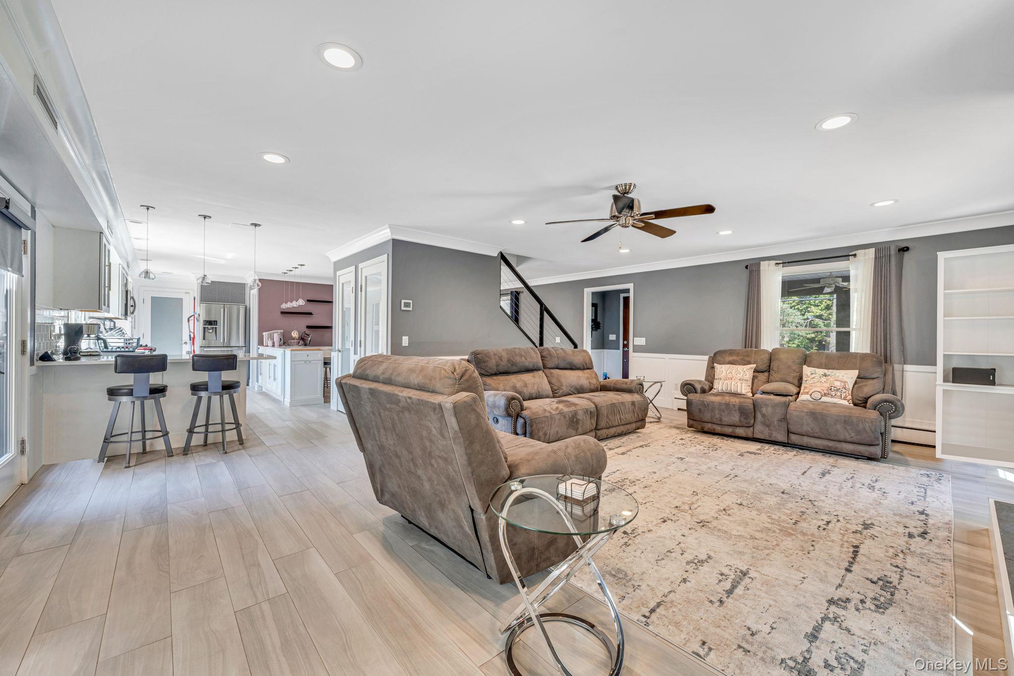 183 Old Country Road Speonk, NY 11972 - Photo 26 of 48 Living room with ornamental molding, light wood-style floors, stairs, recessed lighting, and wainscoting