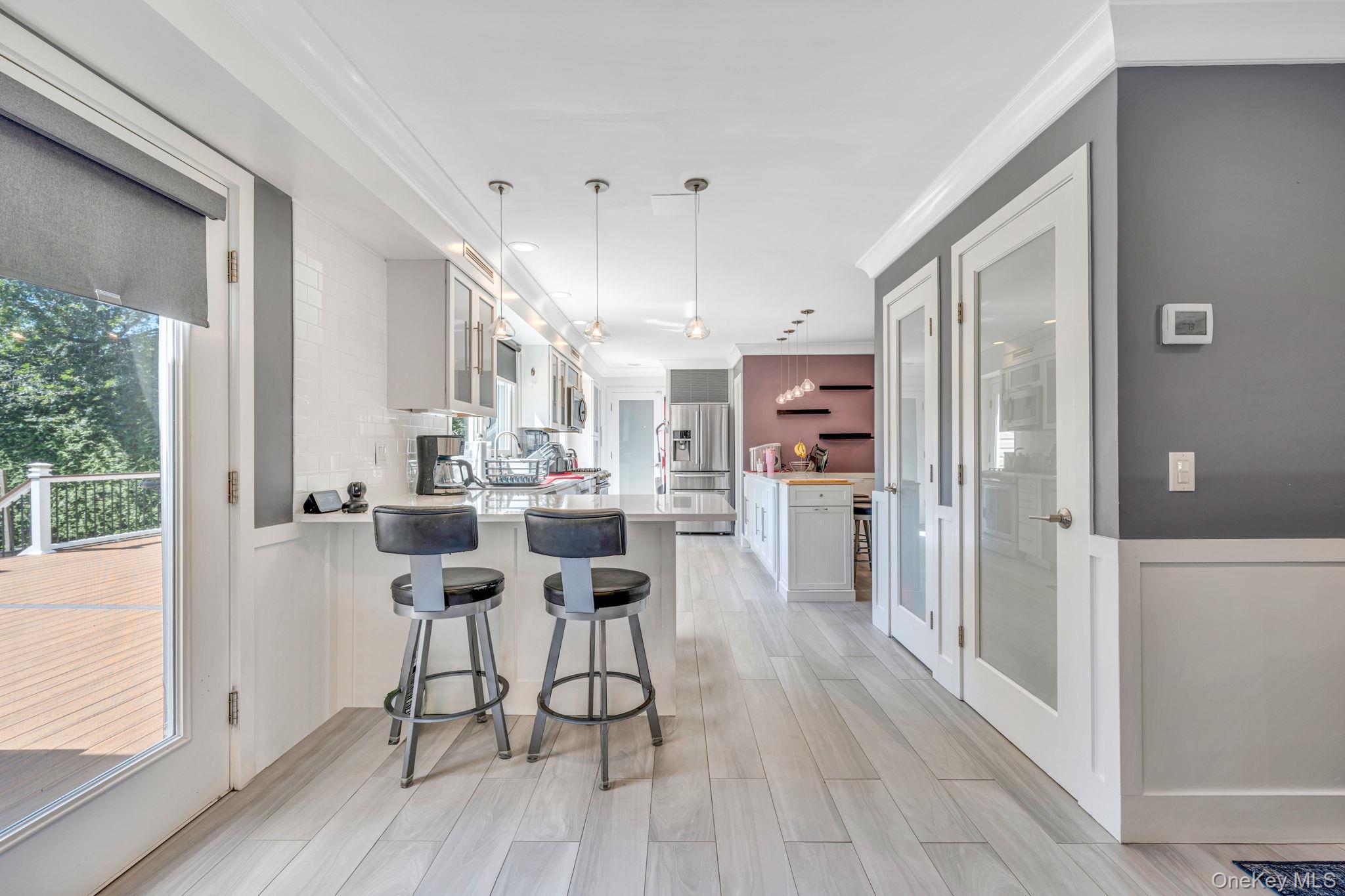 183 Old Country Road Speonk, NY 11972 - Photo 27 of 48 Kitchen featuring white cabinetry, light countertops, a breakfast bar, a peninsula, and stainless steel fridge with ice dispenser