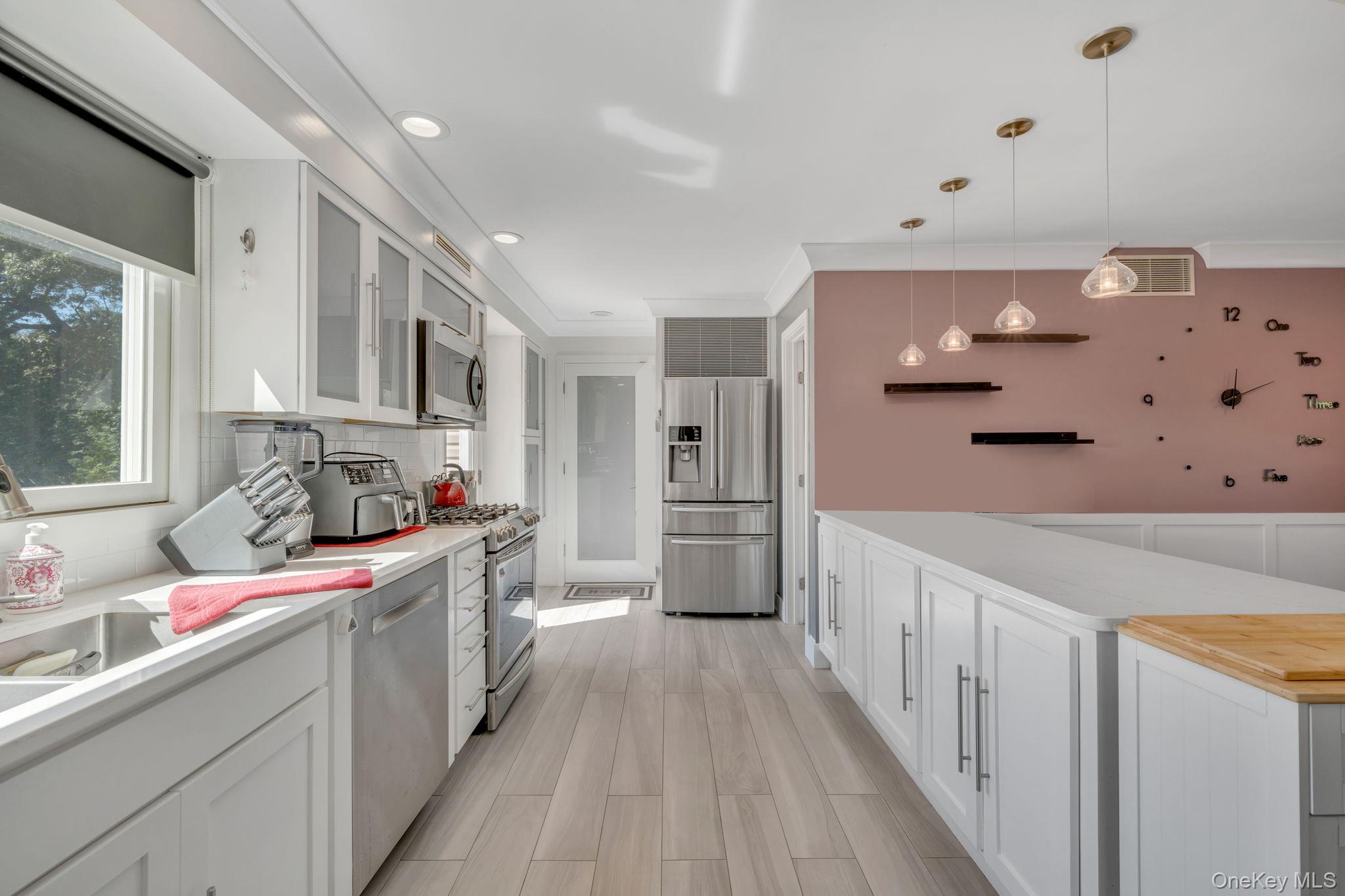 183 Old Country Road Speonk, NY 11972 - Photo 28 of 48 Kitchen featuring white cabinets, stainless steel appliances, hanging light fixtures, glass insert cabinets, and wood finish floors