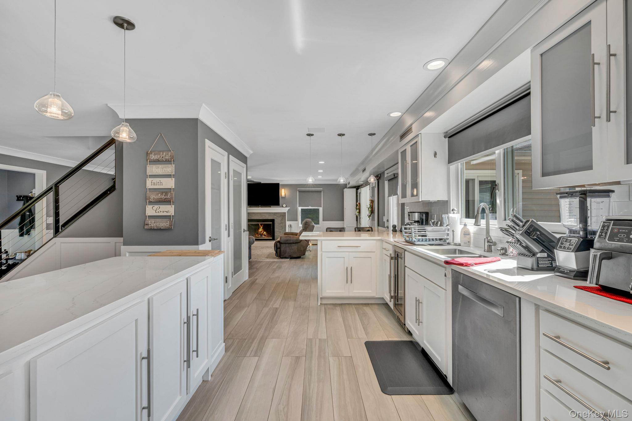 183 Old Country Road Speonk, NY 11972 - Photo 48 of 48 Kitchen featuring hanging light fixtures, white cabinets, dishwasher, glass insert cabinets, and open floor plan