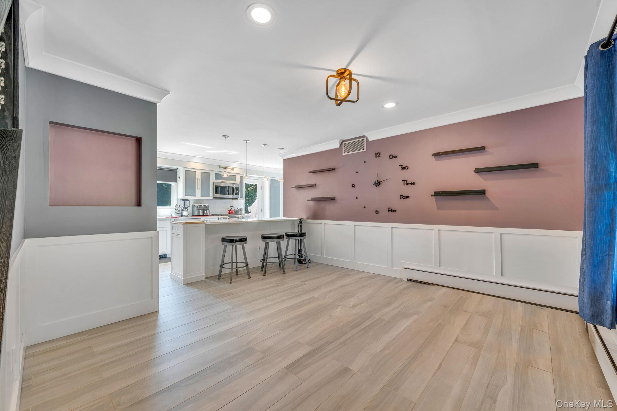 183 Old Country Road Speonk, NY 11972 - Photo 29 of 48 Living room with a baseboard heating unit, light wood-style floors, ornamental molding, a decorative wall, and recessed lighting