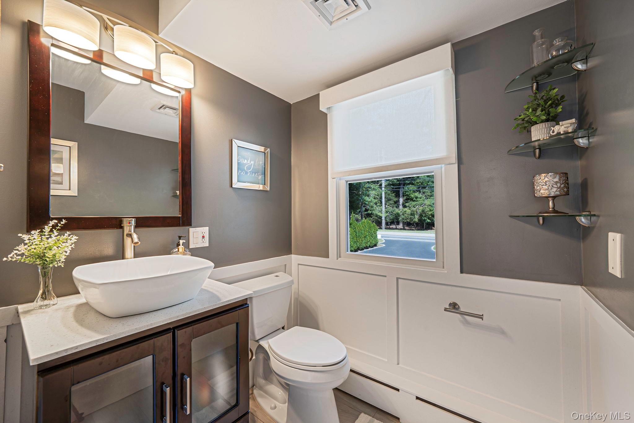 183 Old Country Road Speonk, NY 11972 - Photo 32 of 48 Half bath featuring vanity, a wainscoted wall, a decorative wall, and a baseboard radiator