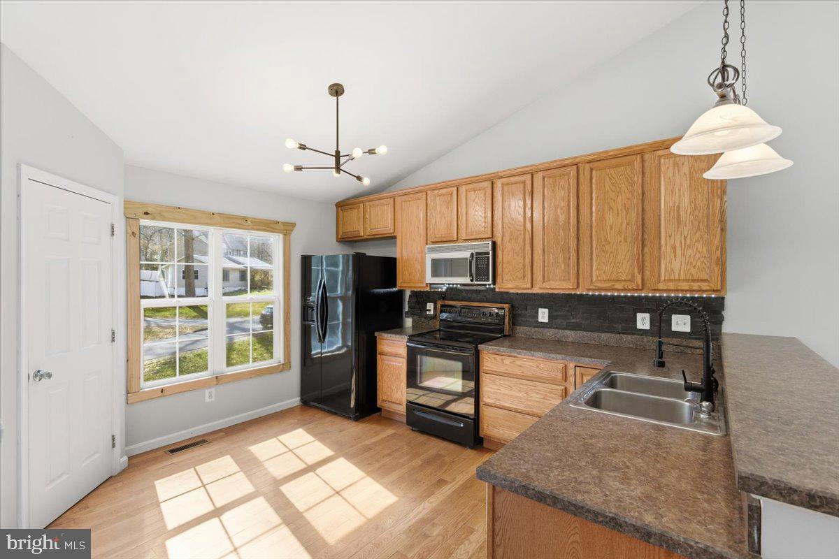 11585 Big Sandy Road Lusby, MD 20657 - Photo 12 of 48 a kitchen with stainless steel appliances granite countertop a stove top oven a sink dishwasher a dining table and chairs with wooden floor
