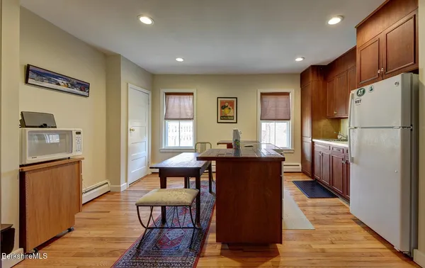 a kitchen with stainless steel appliances granite countertop a refrigerator a sink dishwasher a dining table and chairs with wooden floor