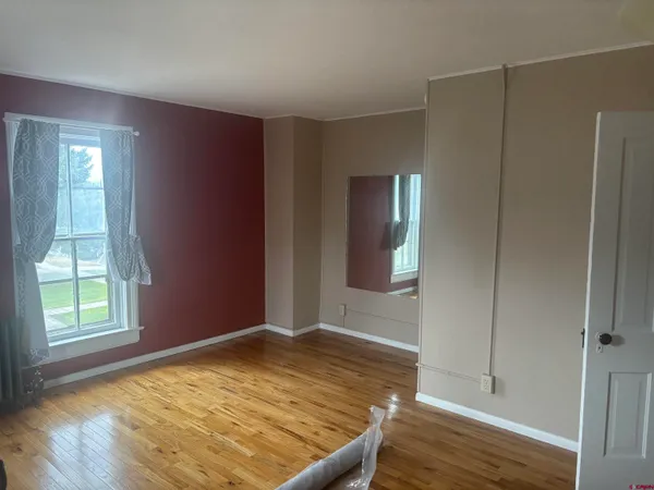 a view of an empty room with window and wooden floor
